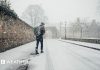 Man walks along a snow covered street with a rucksack on his back