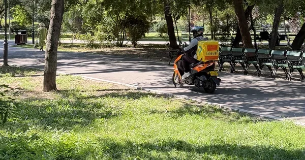 Glovo pe scuter, prin parcul Cișmigiu