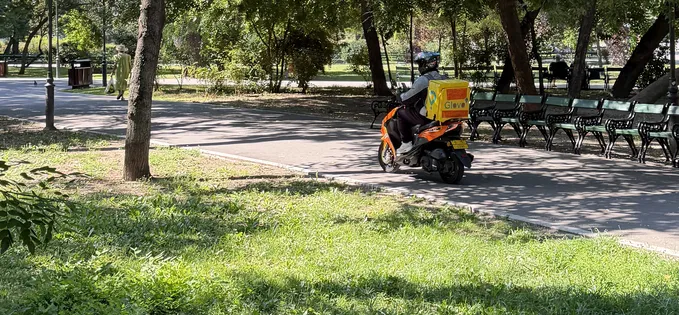 Glovo pe scuter, prin parcul Cișmigiu